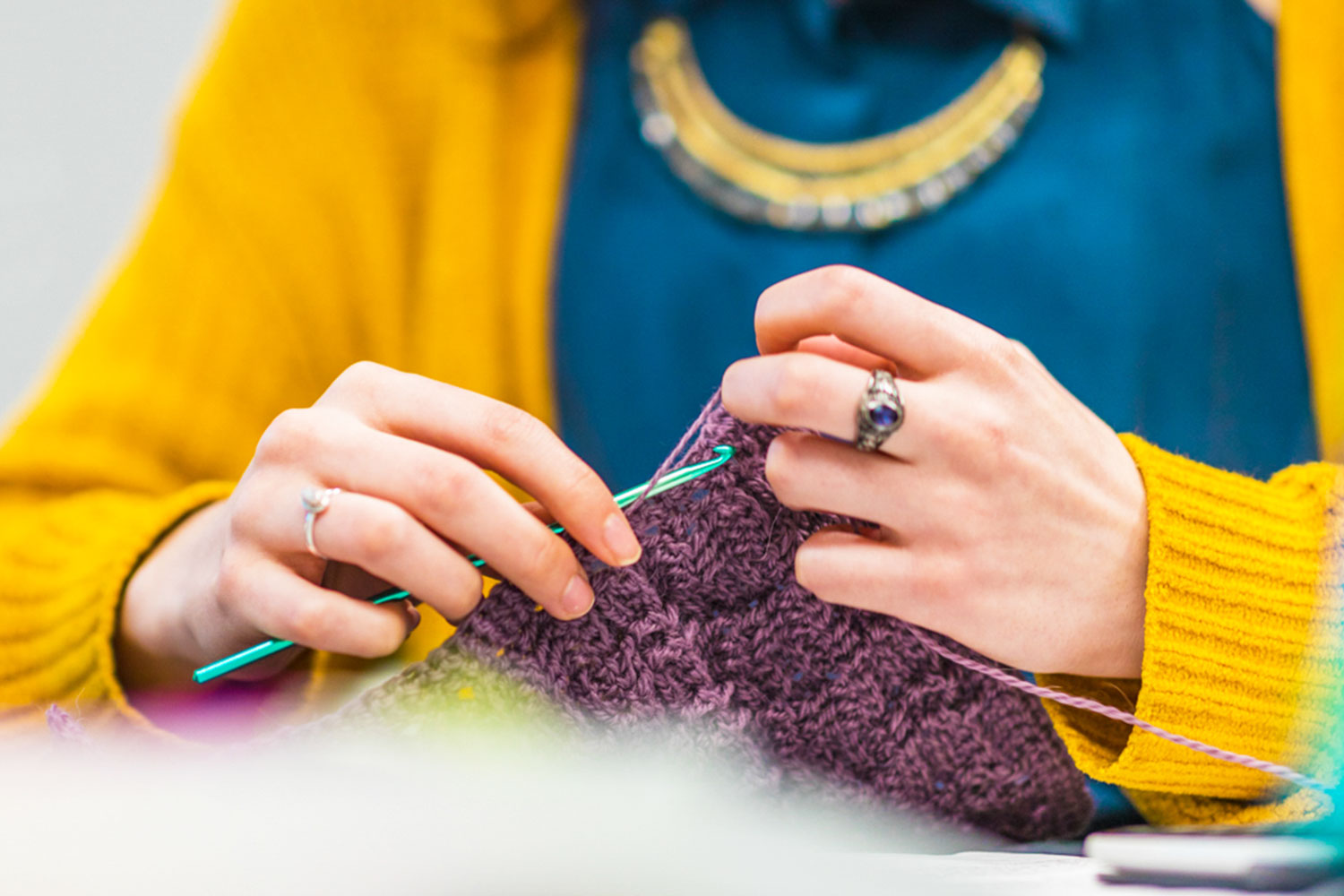 Person working on a knitting project using purple yarn