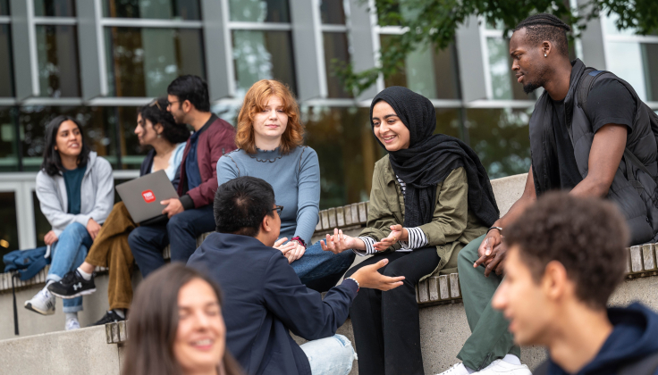 A group of UBC students sit outside the AMS Nest in conversation