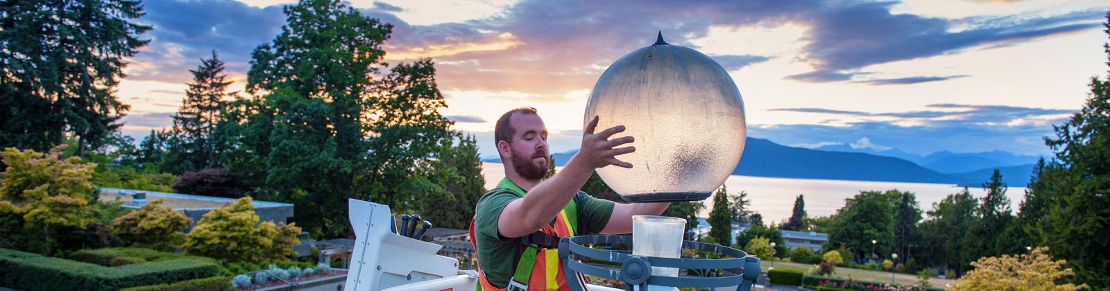 Man changing a lightbulb near UBC Rose Garden