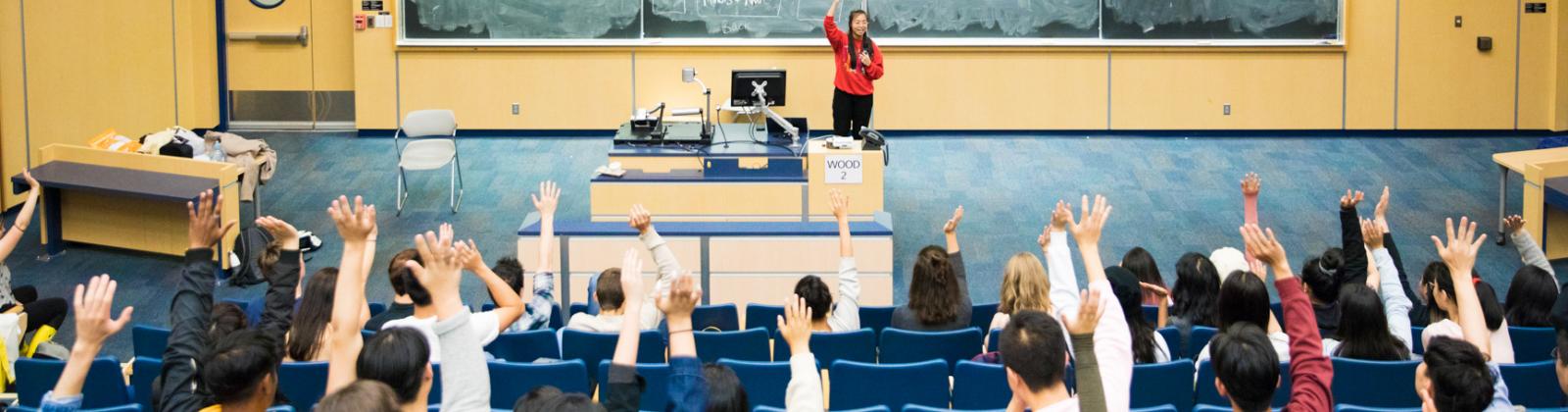 Students raising their hands in a lecture hall
