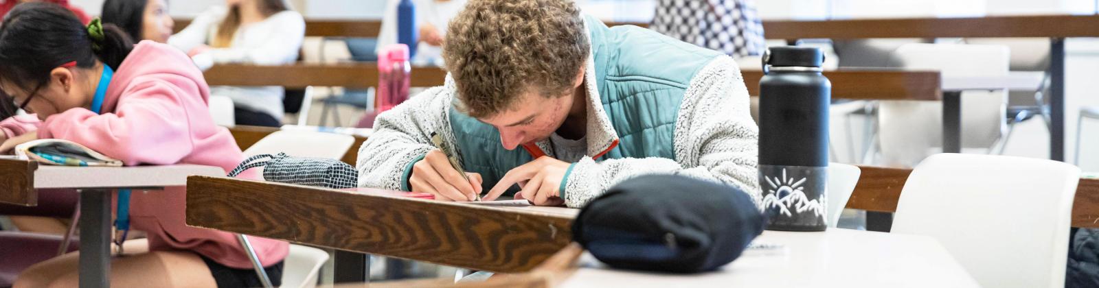 A student focused on writing an exam in a classroom