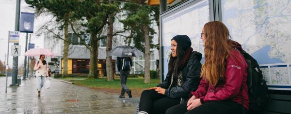 Students sitting at the bench at the bus loop