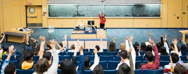 Students raising their hands in a lecture hall