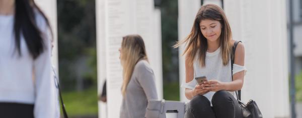UBC student sitting outside looking at her phone