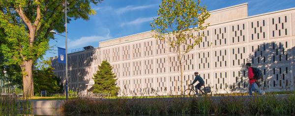 campus building with cyclists going by