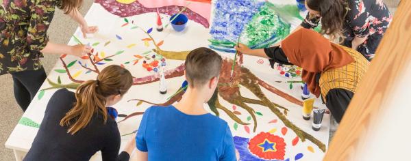 A group of people painting together on a large table