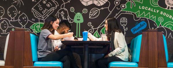A group of students sitting together in a restaurant booth enjoying a meal together