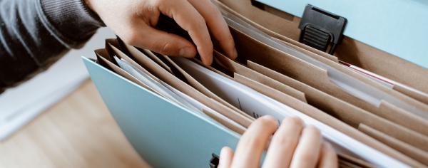 Close up of a student's hands flipping through a file folder containing documents