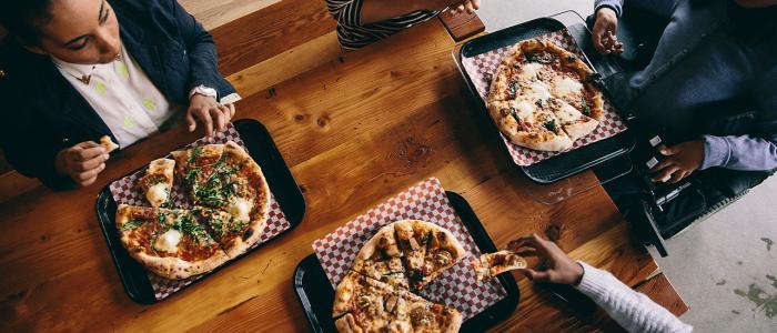 Bird's eye view of three pizzas on a wooden table