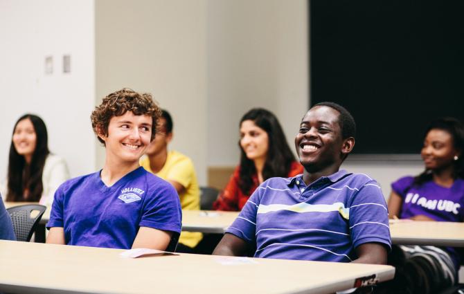 Two students sitting together in a classroom laughing and smiling amongst themselves