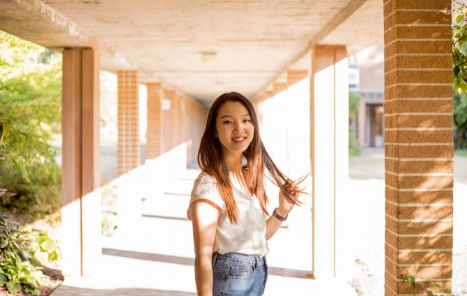 Student, Claire Song, standing in an outdoor corridor