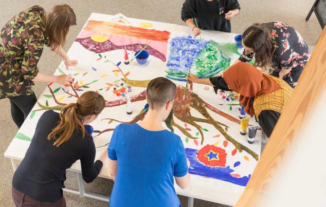 A group of people painting together on a large table