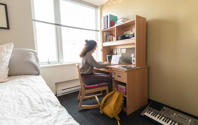 A student working on her laptop in her residence