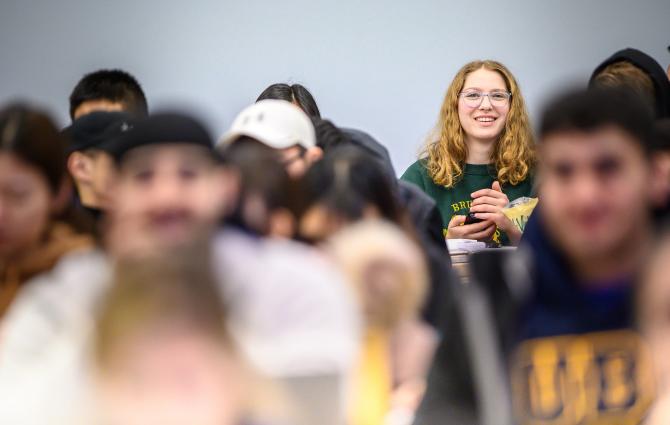 A student smiling while sitting in a classroom amongst other students