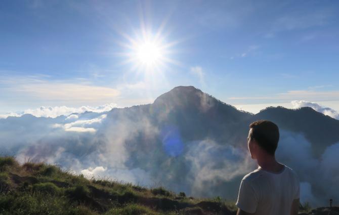 student on a landscape above the clouds, looking over the horizon