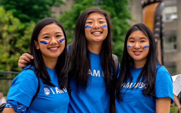 Three UBC Orientation Leaders wearing blue t-shirts and face paint.
