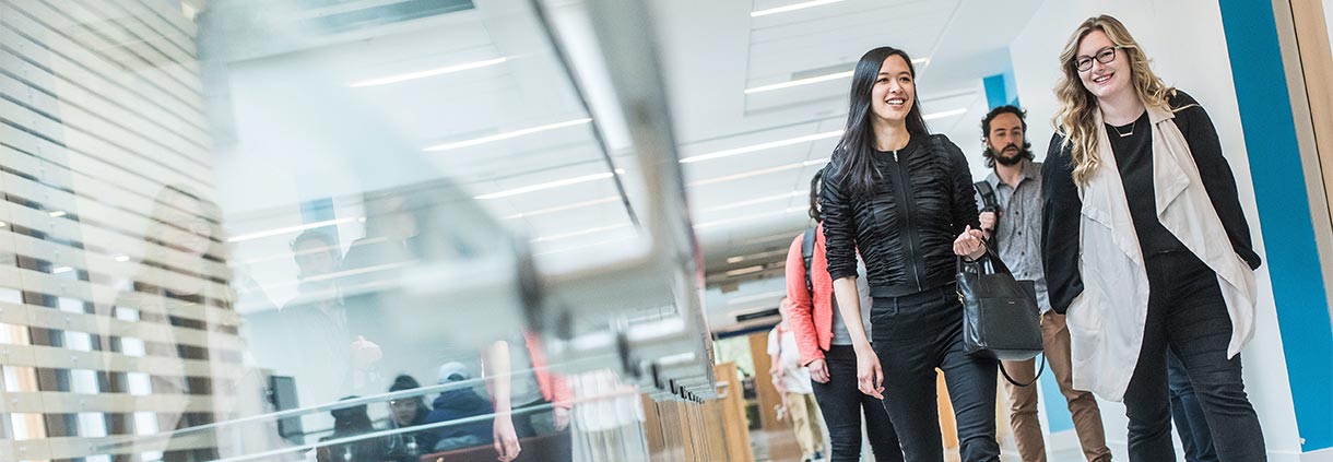 Four UBC graduate students walking down the hallway on the Vancouver campus while in conversation